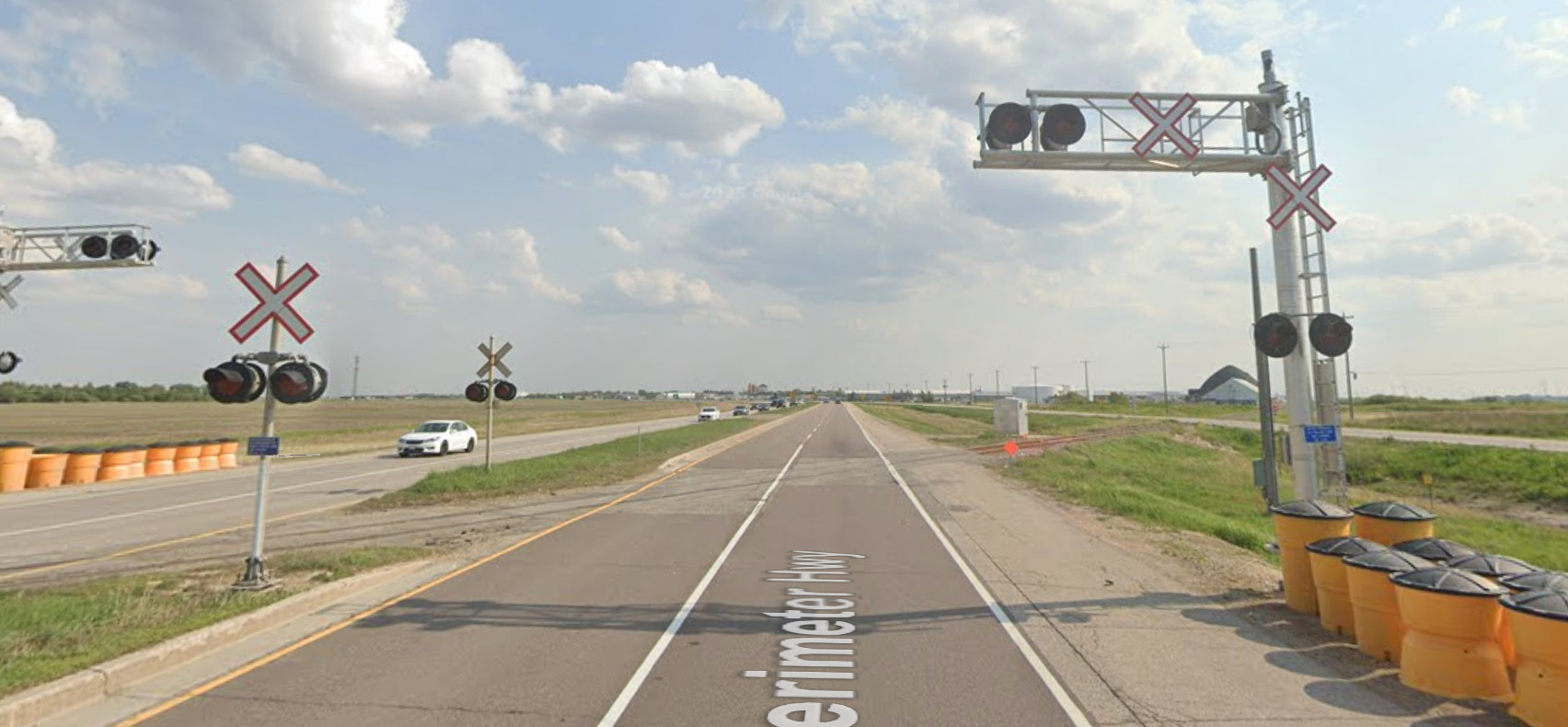 Screenshot of Google Street View, just a little bit further along the road. A railroad crosses the 4-lane highway at a sharp angle.