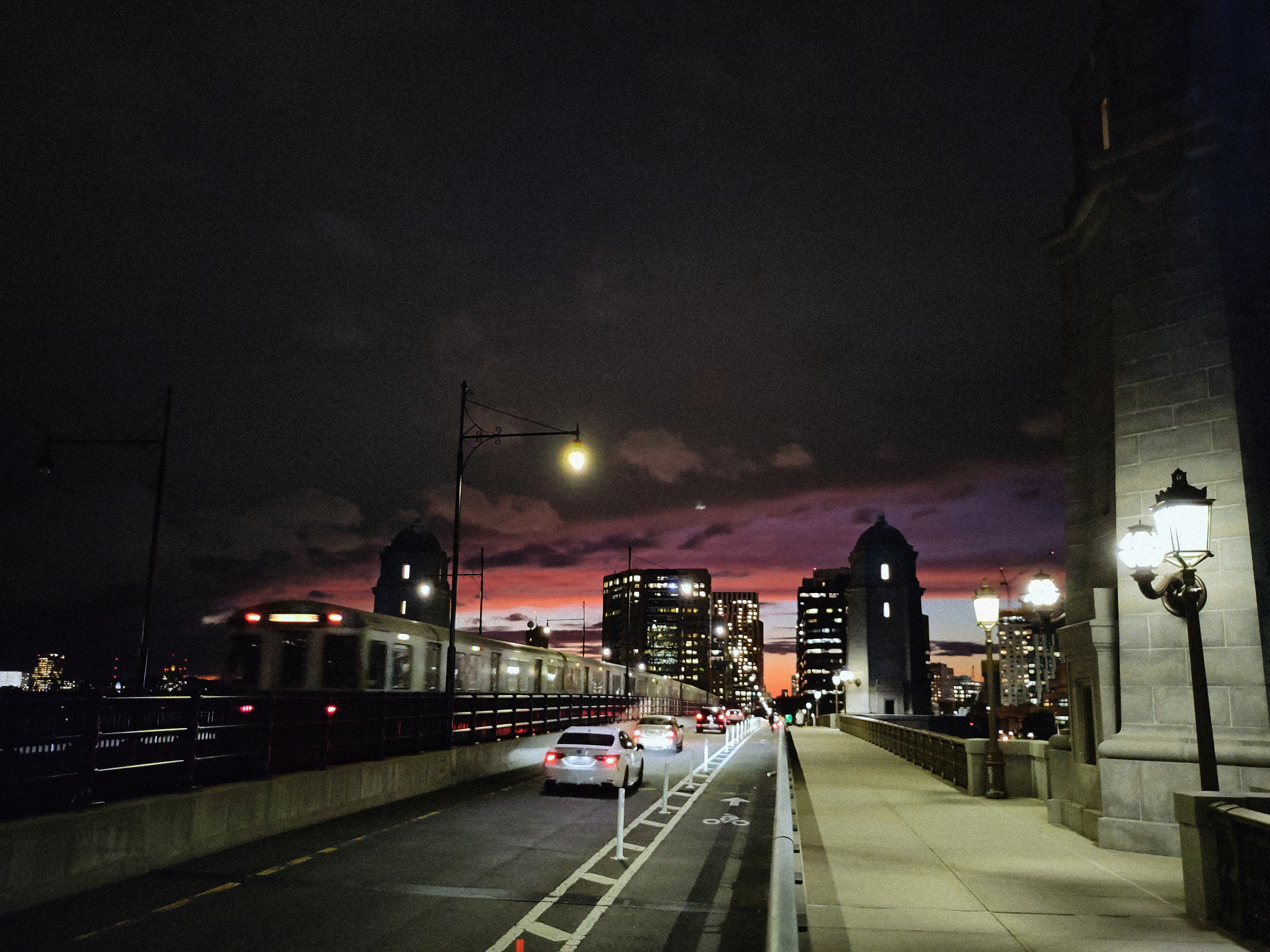 A sunset view of an old Alewife-bound MBTA Red Line train crossing a bridge towards Kendall.